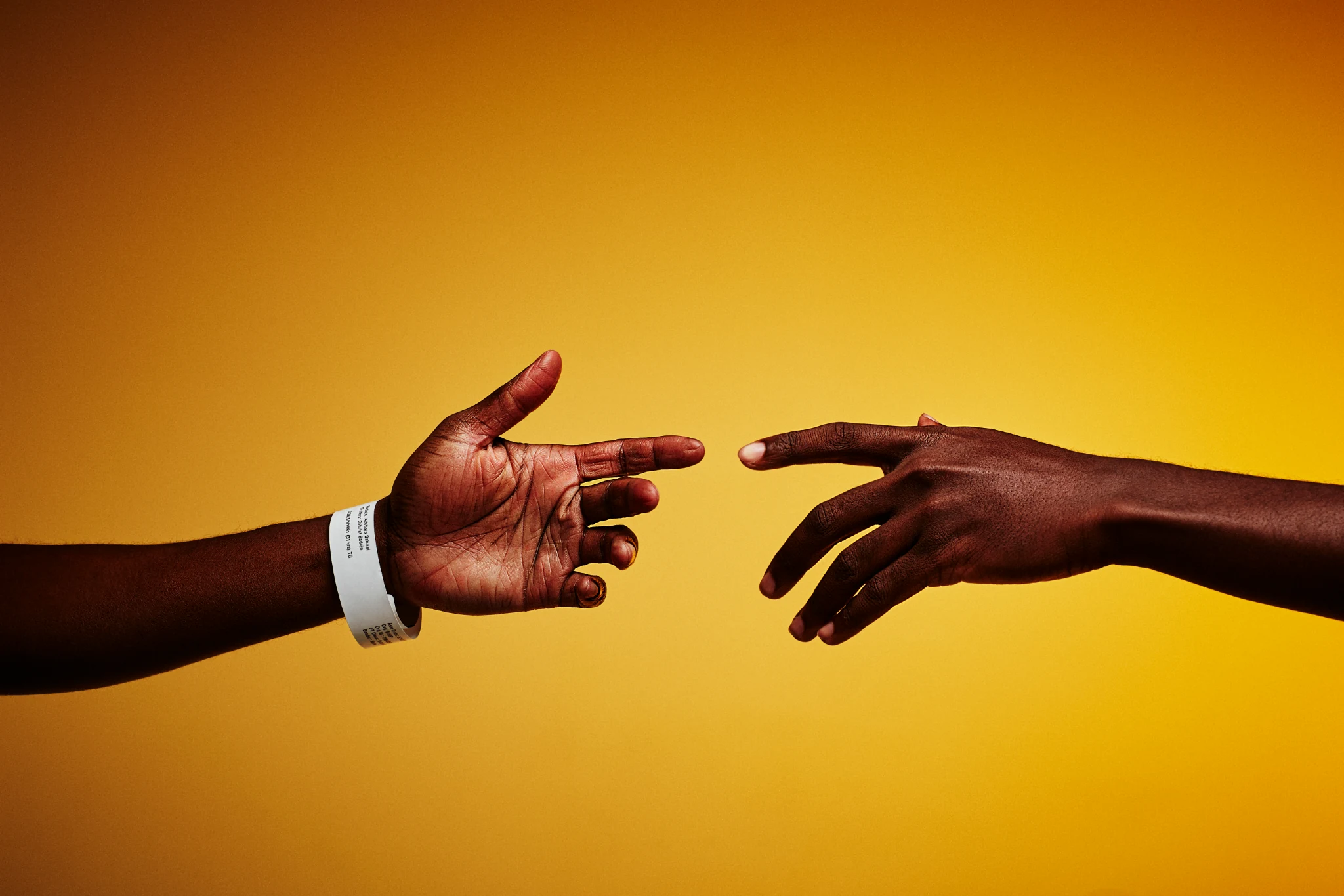 Two hands reaching toward each other against a gold background